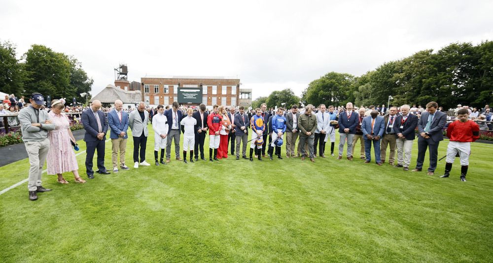 Jockeys and journalists observe a minute's silence for commentator John Hunt and his family following Tuesday's tragedy